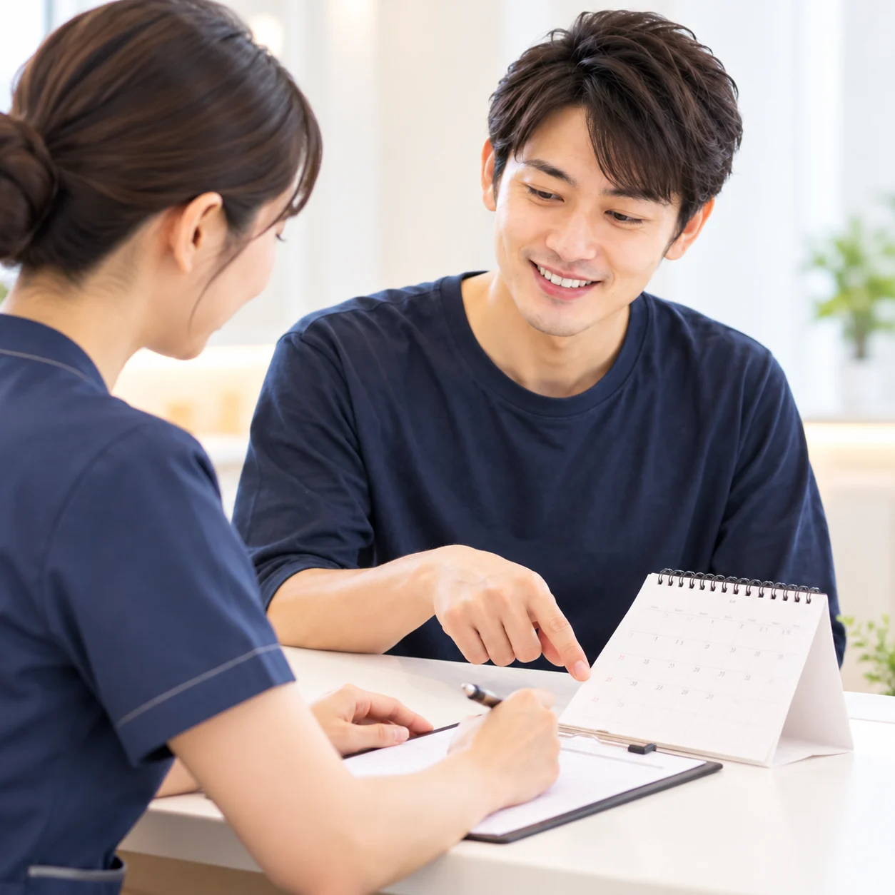 男性患者と次回の予約日を相談するイメージ